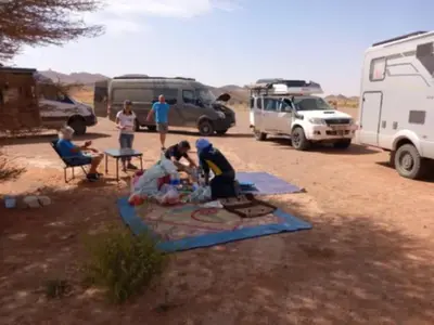 a group of people sitting around a table in a field at Auberge Hassi Fougani in Tafraoute Sidi Ali