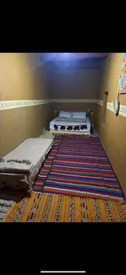 two beds in a room with a rug on the floor at Ryad lcaid in Tissint