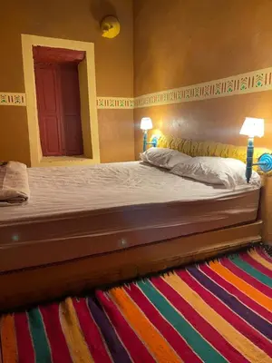 a bedroom with a bed with two lamps and a colorful rug at Ryad lcaid in Tissint