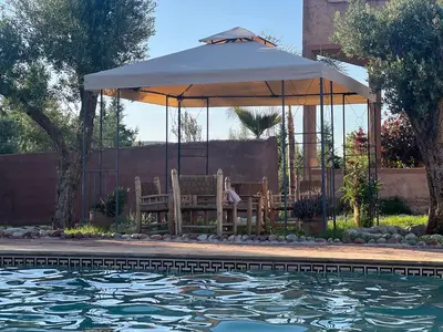 a gazebo with a person sitting in it next to a pool at Escapade famille - vue panoramique et piscine privée in Aït Ghemat