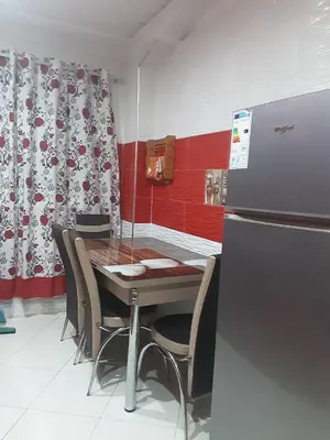 a dining room with a table and chairs and a refrigerator at Appartement à louer à imouzzar kander in Imouzzer Kandar
