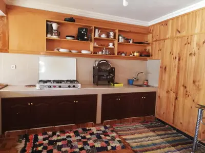 a kitchen with wooden cabinets and a stove at Gite Oukaimeden in Oukkainrdem