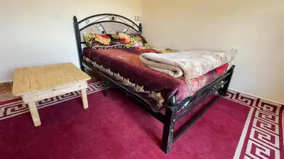 a bedroom with a bed and a table on a purple carpet at Gite Oukaimeden in Oukkainrdem