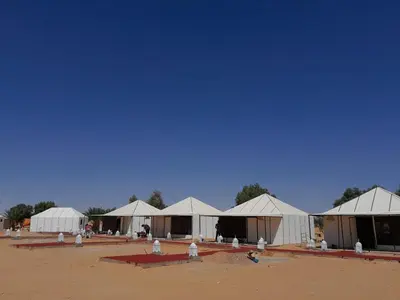 a row of white tents in a field at sahara oasis camp in Merzouga