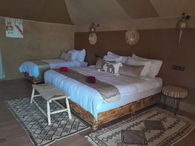 a bedroom with two beds and a chair at sahara oasis camp in Merzouga