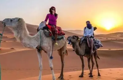 two people riding on the camel in the desert at Camp Golden Desert Morocco in Mhamid