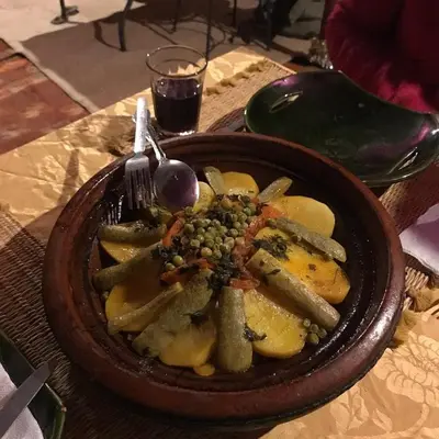 a bowl of food with a fork and vegetables on a table at Camp Golden Desert Morocco in Mhamid