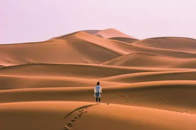 a man standing on a sand dune in the desert at Erg Chigaga Regency Camp in El Gouera
