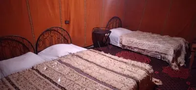 a room with three beds with white sheets at Erg Chigaga Regency Camp in El Gouera