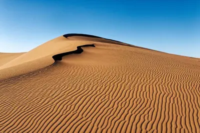 a sand dune in the middle of a desert at Erg Chigaga Regency Camp in El Gouera