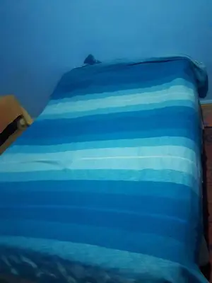 a bed with blue and white sheets on it at Chez Meriem in Merzouga