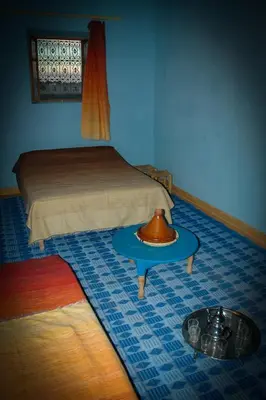a bedroom with a bed and a table with a bowl on it at Chez Meriem in Merzouga