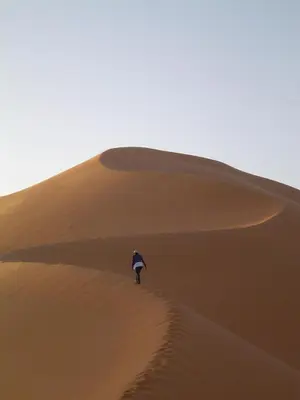 a person walking on a sand dune in the desert at Chez Meriem in Merzouga