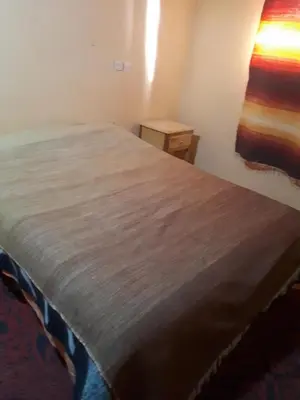 a bed in a room with a wooden bedspread at Chez Meriem in Merzouga