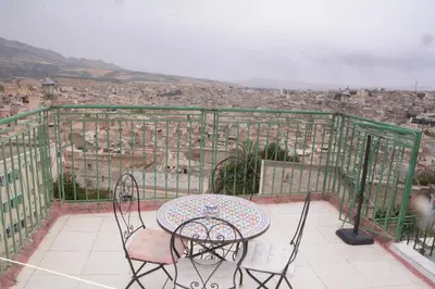 a table and chairs on a balcony overlooking a city at Dar El Karam Fez in Fès
