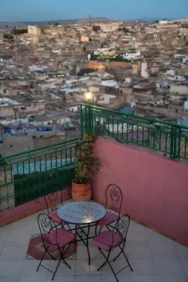 a table and chairs on a balcony overlooking a city at Dar El Karam Fez in Fès