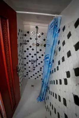 a bathroom with a shower with a blue curtain at Dar El Karam Fez in Fès