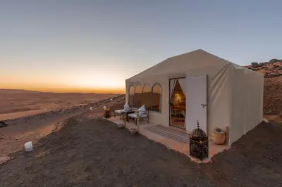 a tent in the desert with the sunset in the background at Soleil Camp & Camel Trekking in Merzouga