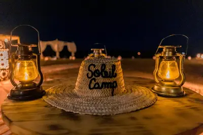 two lights sitting on a table with a towel at Soleil Camp & Camel Trekking in Merzouga