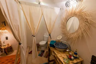 a bathroom with a sink and a mirror and a toilet at Soleil Camp & Camel Trekking in Merzouga