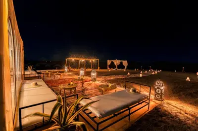 a patio with tables and lights at night at Soleil Camp & Camel Trekking in Merzouga