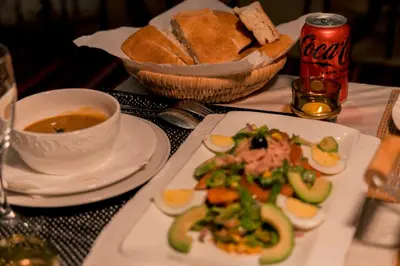 a table with a plate of food and a bowl of bread at Soleil Camp & Camel Trekking in Merzouga
