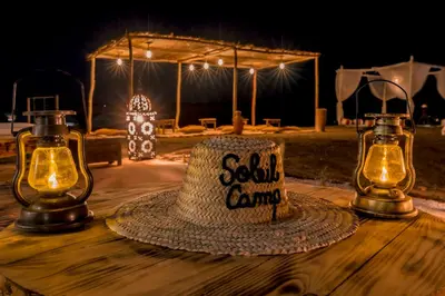 a hat sitting on a wooden table with two lights at Soleil Camp & Camel Trekking in Merzouga