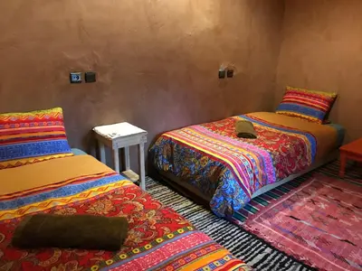 a room with two beds and a table in it at Kasbah Mashallah in Tagounite