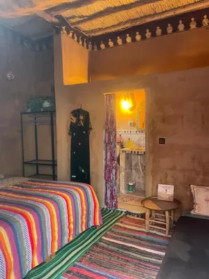a bedroom with a bed and a table in a room at Kasbah Mashallah in Tagounite