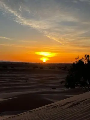 a sunset in the desert with the sun setting at Camp Mbark authentic in Mhamid