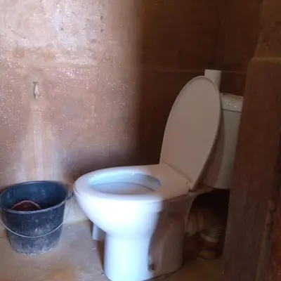 a white toilet in a bathroom with a bucket at Camp Mbark authentic in Mhamid