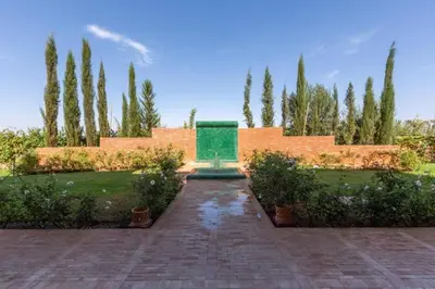 a garden with a fountain and trees and a brick wall at Somptueuse Villa louée avec le personnel de maison in Marrakech