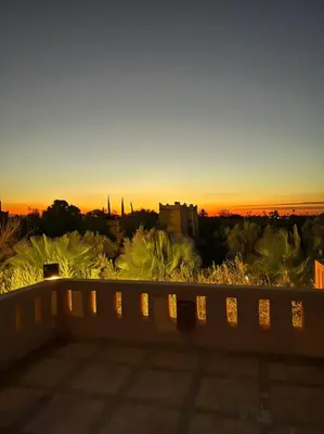 a view of the sunset from a balcony with a bench at Somptueuse Villa louée avec le personnel de maison in Marrakech