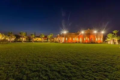 a large building with lights in a field at night at Somptueuse Villa louée avec le personnel de maison in Marrakech