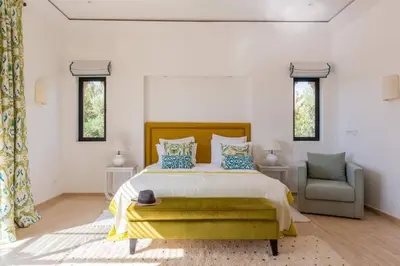 a bedroom with a bed and a chair and windows at Somptueuse Villa louée avec le personnel de maison in Marrakech