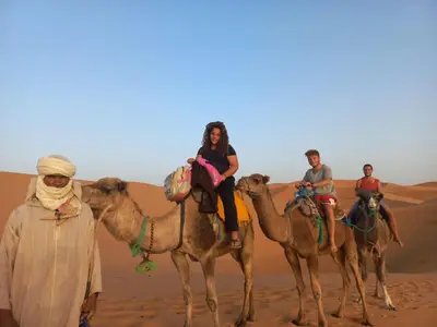a group of people riding on camels in the desert at Nirvana Desert Camp in Merzouga