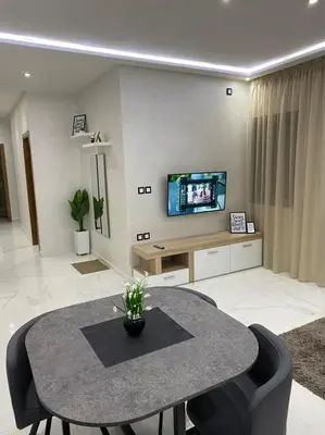 a living room with a table and a tv at Appart luxueux sécurisé parking 10 min Medina in Fès