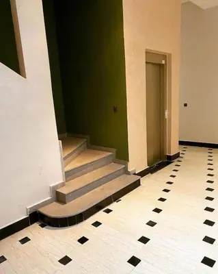 a hallway with stairs in a building with green walls at Appart luxueux sécurisé parking 10 min Medina in Fès