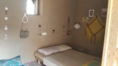 a bedroom with two beds and decorations on the wall at Dar Etran in Kasr Bounou