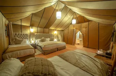 a bedroom with two beds in a tent style room at Nomadic Sands Retreat in Merzouga