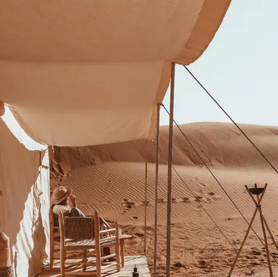a man sitting in a chair in the desert at Nomadic Sands Retreat in Merzouga