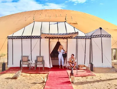 a man and a woman standing inside of a tent at Nomadic Sands Retreat in Merzouga