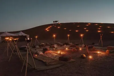 a group of people standing on top of a hill at night at Nomadic Sands Retreat in Merzouga