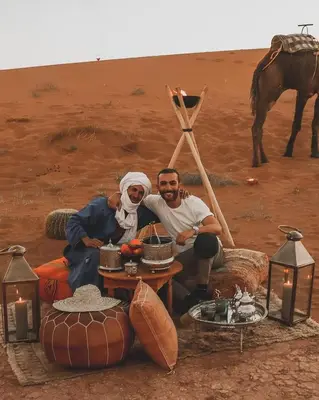 two men sitting around a table in the desert at Nomadic Sands Retreat in Merzouga