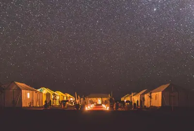 a group of huts under a starry sky at night at Nomadic Sands Retreat in Merzouga