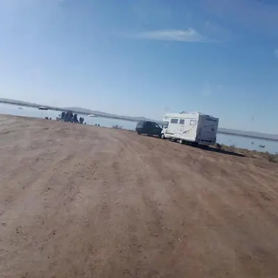 a truck parked on a dirt road next to the water at ERG MERZOUGA SAHARA CAMP in Merzouga