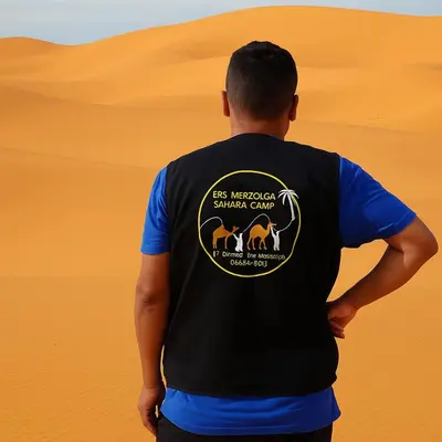 a man wearing a black and blue shirt at ERG MERZOUGA SAHARA CAMP in Merzouga