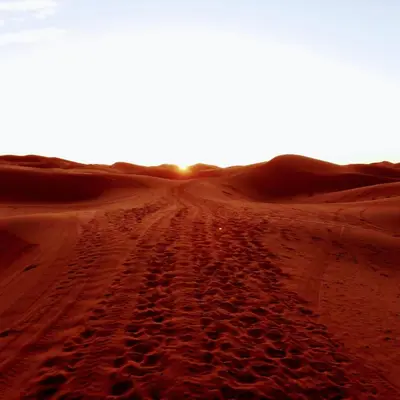 a dirt road in the desert at sunset at ERG MERZOUGA SAHARA CAMP in Merzouga