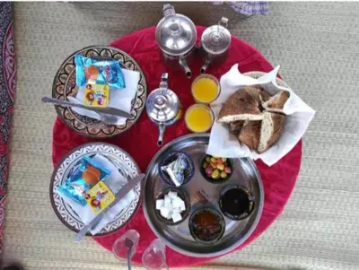 a red table with a plate of food and toast at ERG MERZOUGA SAHARA CAMP in Merzouga