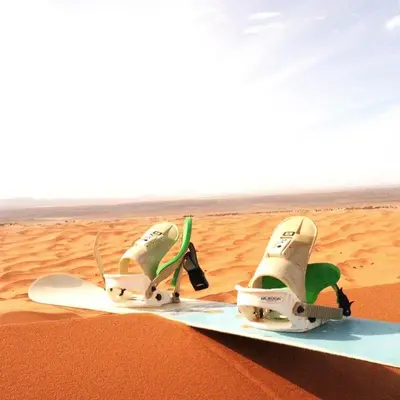 a pair of shoes sitting on a snowboard in the sand at Bivouac la fibule des Dunes in Merzouga